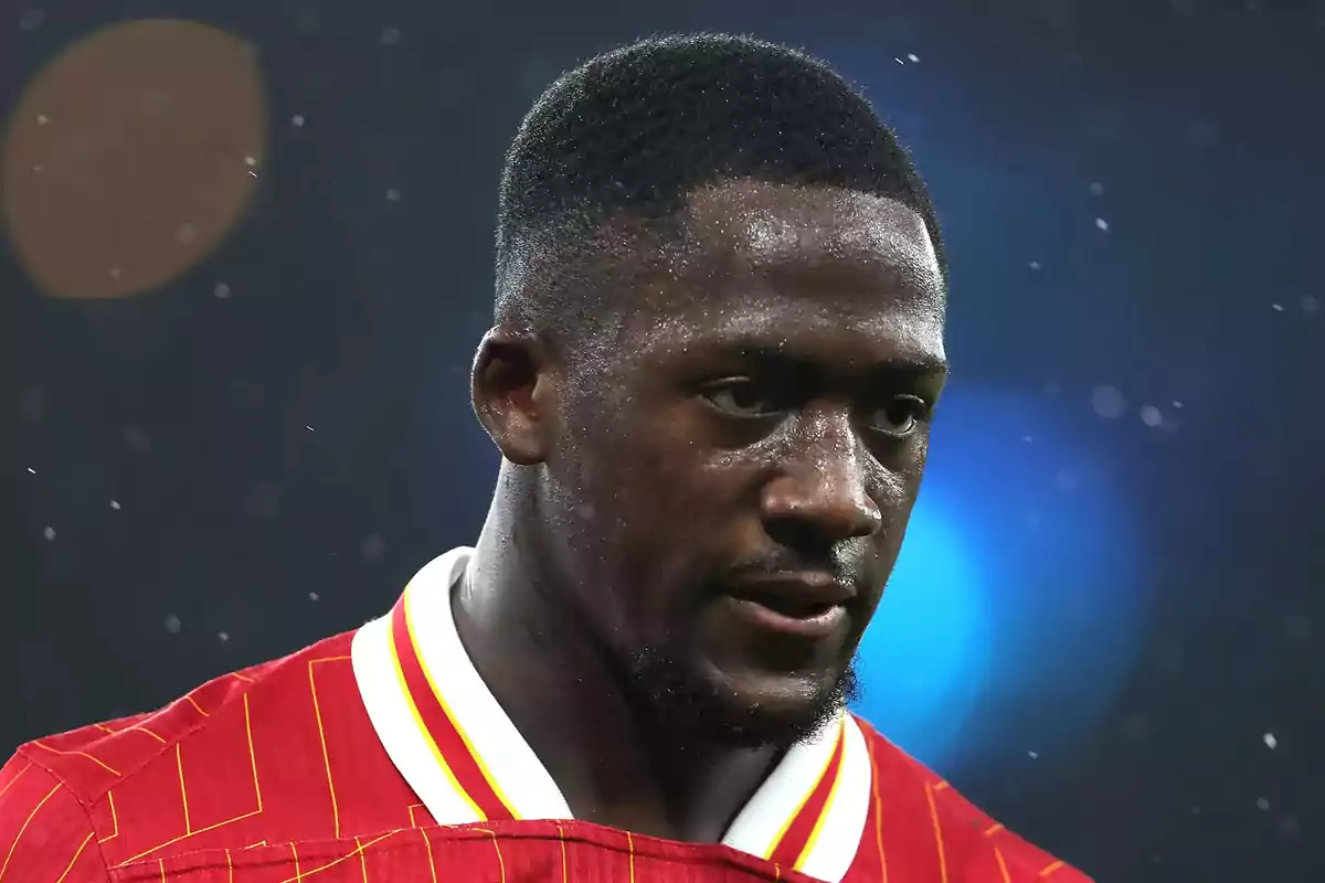 Soccer player in a red jersey with yellow details in the foreground during a match in the rain Soccer player in a red jersey with yellow details in the foreground during a match in the rain