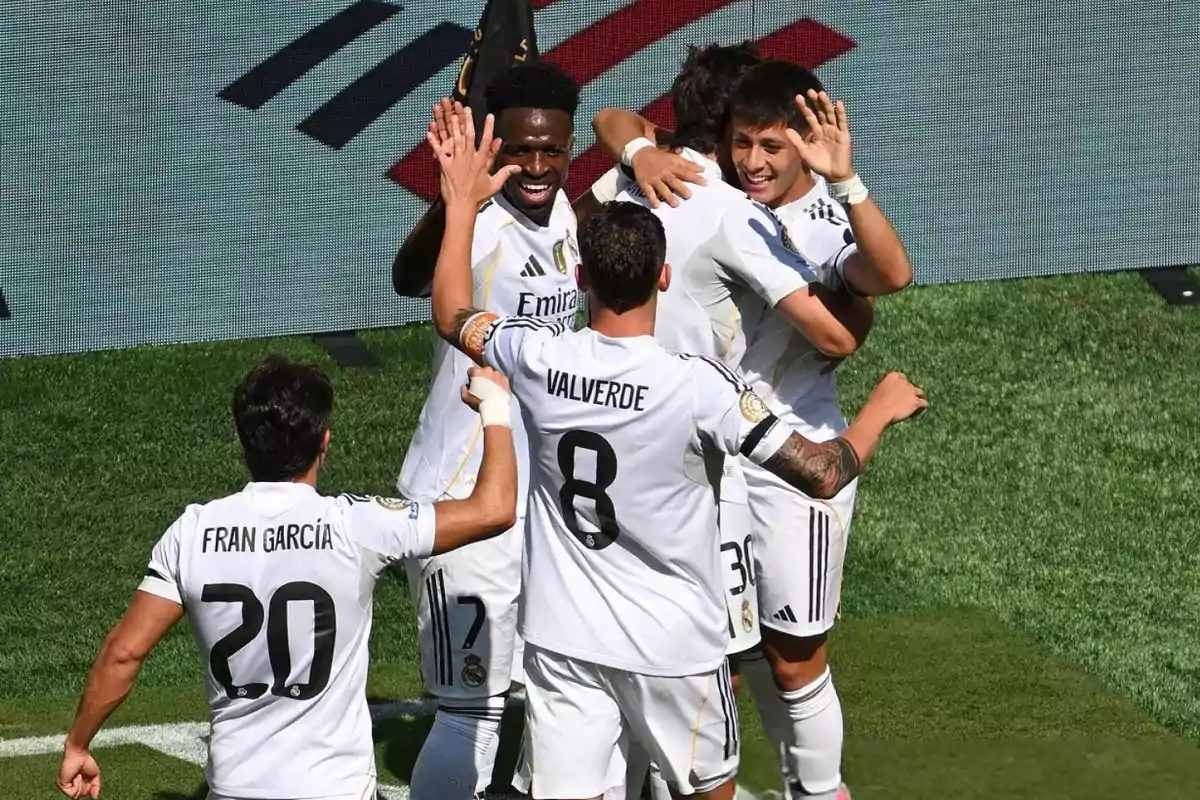 Jugadores del Real Madrid celebran un gol abrazándose y chocando las manos en el campo de fútbol
