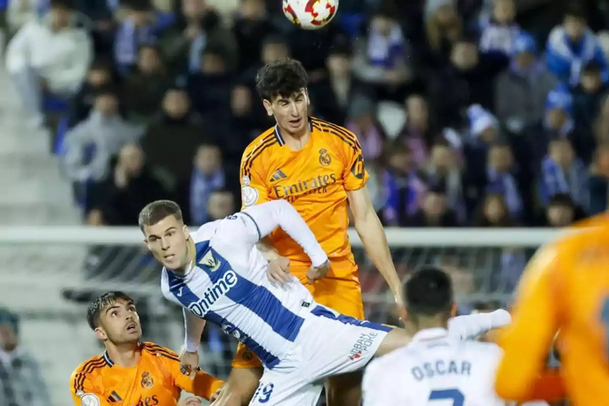Soccer players from two different teams compete for the ball in a match; one of them jumps to head it while the other tries to intercept. Soccer players from two different teams compete for the ball in a match; one of them jumps to head it while the other tries to intercept.