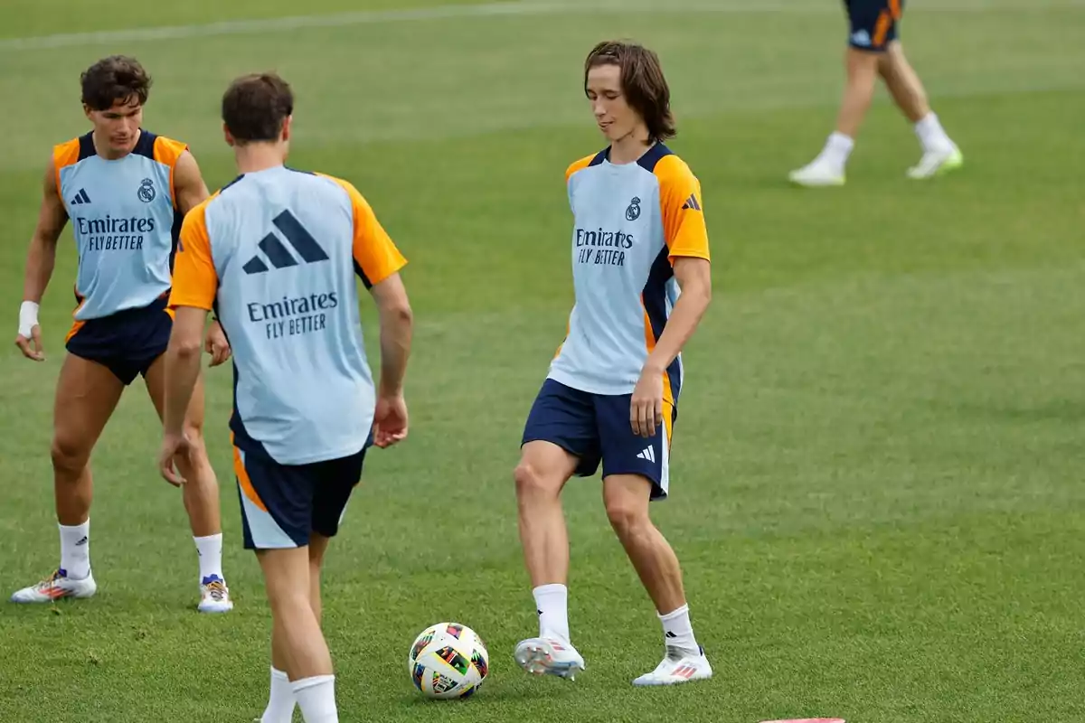 Real Madrid players training on the field in blue and orange training uniforms Real Madrid players training on the field in blue and orange training uniforms