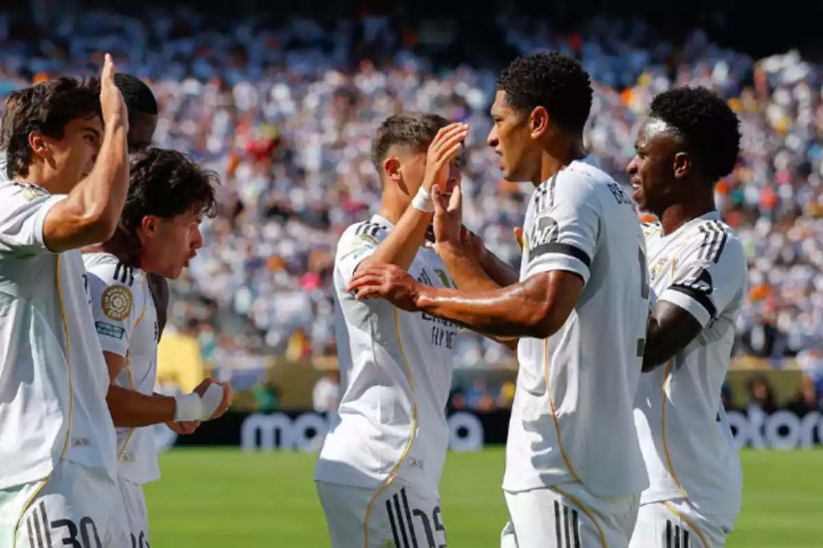 Jugadores de fútbol del Real Madrid celebran un gol en el campo rodeados de aficionados en las gradas Jugadores de fútbol del Real Madrid celebran un gol en el campo rodeados de aficionados en las gradas