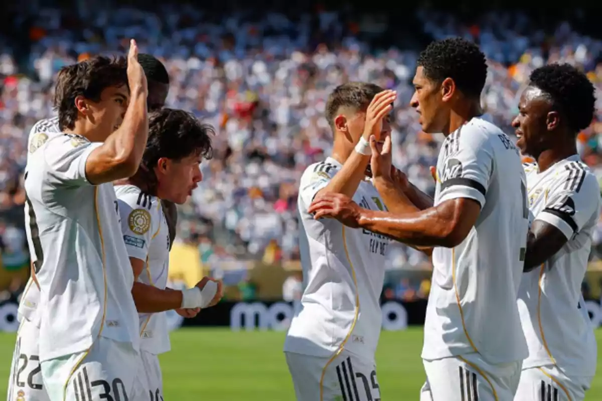 Jugadores de fútbol del Real Madrid celebran un gol en el campo durante un partido con el estadio lleno de aficionados al fondo Jugadores de fútbol del Real Madrid celebran un gol en el campo durante un partido con el estadio lleno de aficionados al fondo