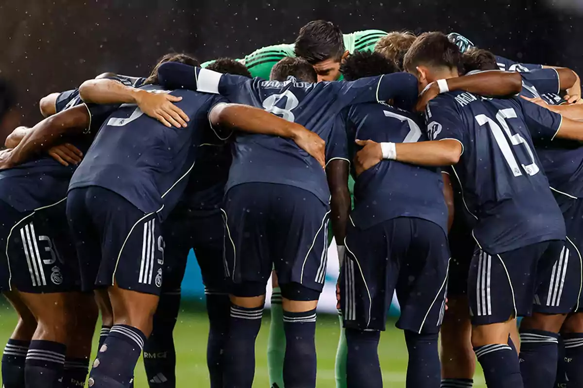 Soccer players gathered in a circle with their arms around each other before starting a match