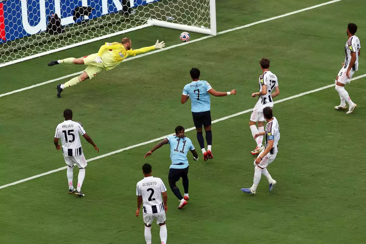 A goalkeeper dives to try to stop a ball heading toward the goal while several players watch the play during a soccer match. A goalkeeper dives to try to stop a ball heading toward the goal while several players watch the play during a soccer match.