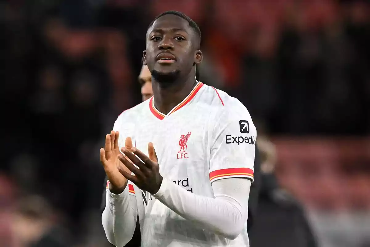 Futbolista del Liverpool con uniforme blanco aplaudiendo en el campo Futbolista del Liverpool con uniforme blanco aplaudiendo en el campo