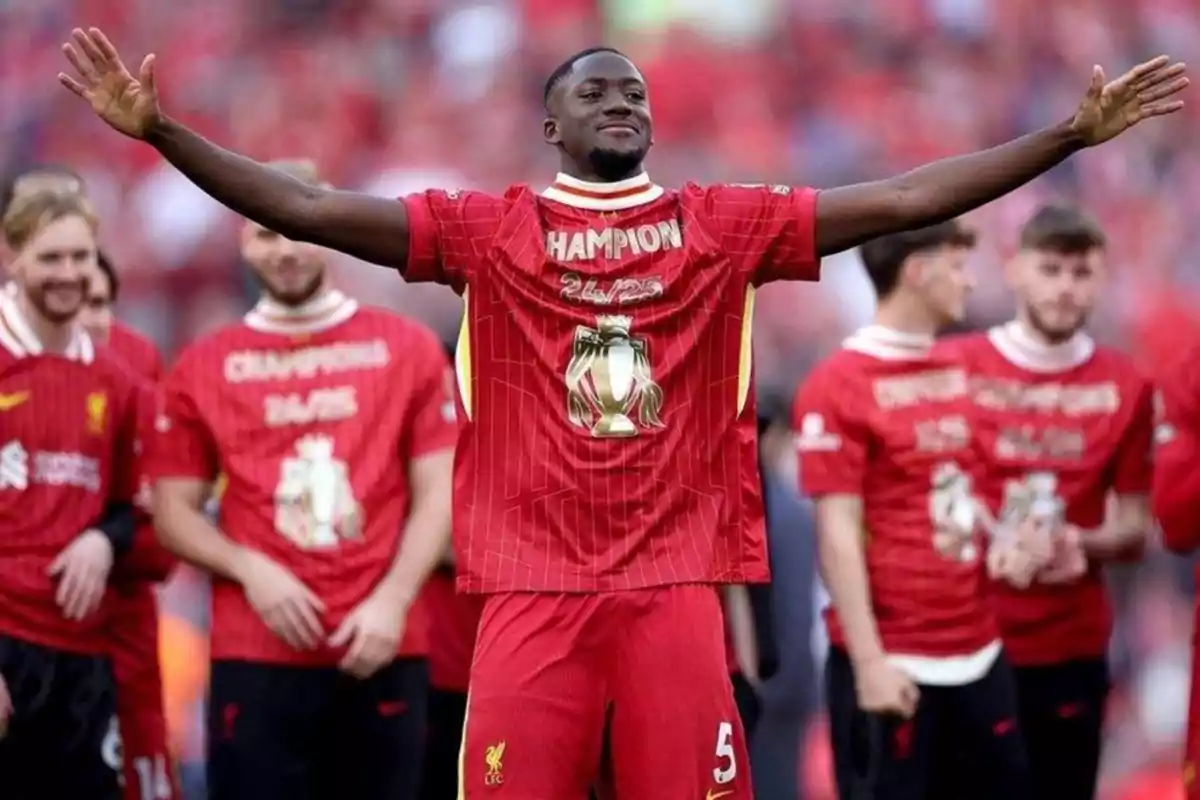 Liverpool footballer celebrating with arms outstretched alongside teammates wearing red champion jerseys Liverpool footballer celebrating with arms outstretched alongside teammates wearing red champion jerseys