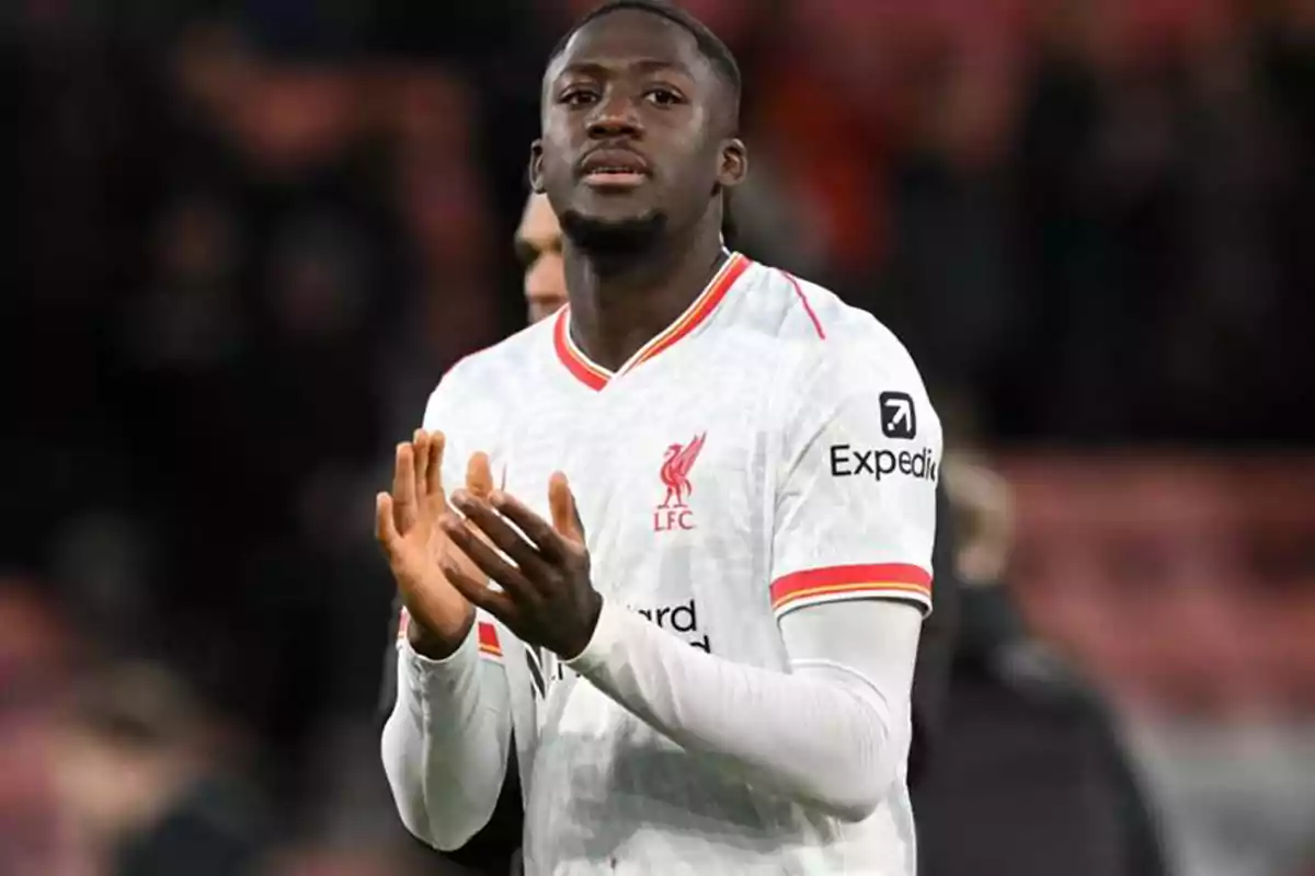 Futbolista con uniforme blanco del Liverpool aplaudiendo en el campo