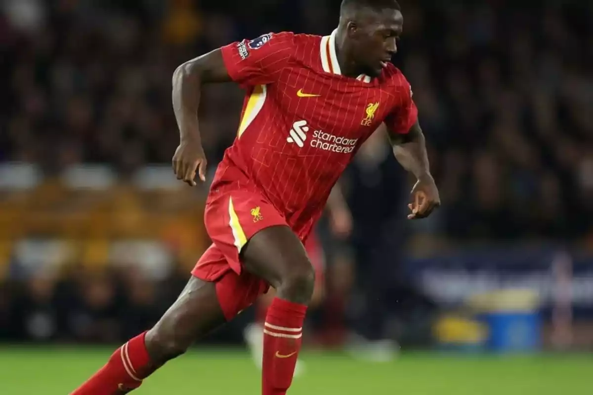 Soccer player in a red Liverpool uniform running on the field during a match Soccer player in a red Liverpool uniform running on the field during a match