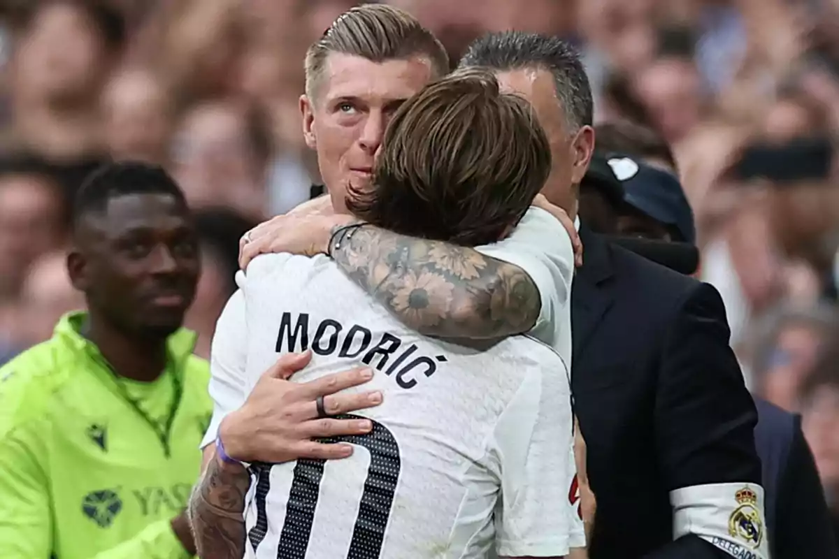 Dos futbolistas del Real Madrid se abrazan emocionados en el campo durante un partido, uno de ellos lleva la camiseta con el nombre Modric. Dos futbolistas del Real Madrid se abrazan emocionados en el campo durante un partido, uno de ellos lleva la camiseta con el nombre Modric.