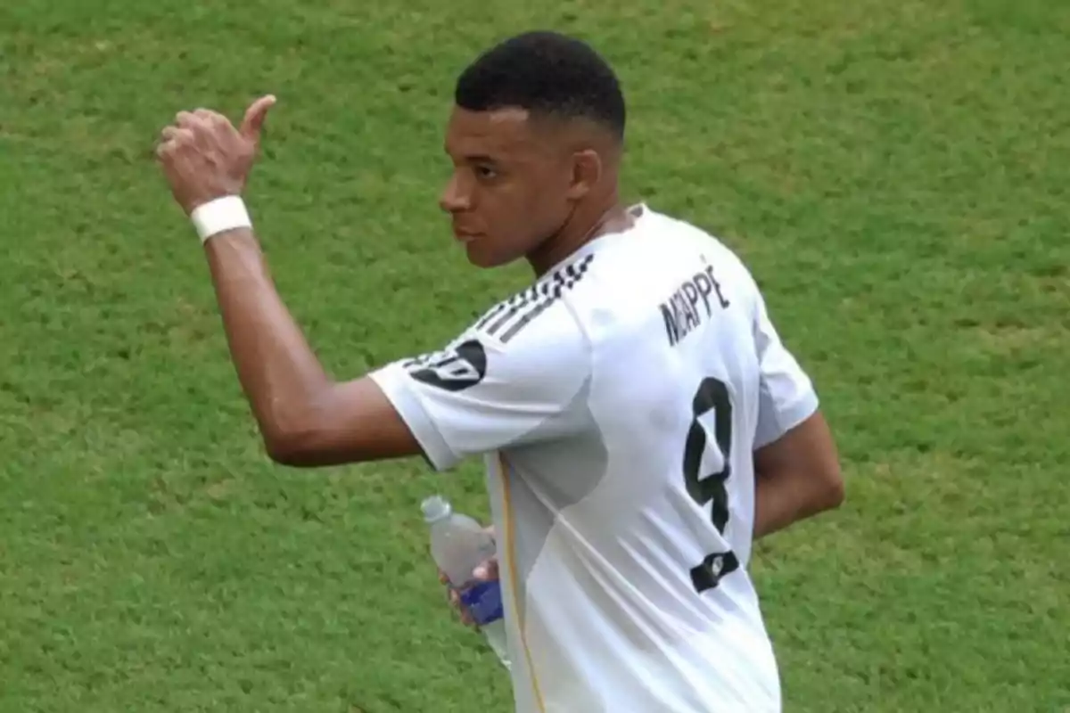 Soccer player wearing a white jersey with the number 9 giving a thumbs up on a grass field while holding a water bottle Soccer player wearing a white jersey with the number 9 giving a thumbs up on a grass field while holding a water bottle