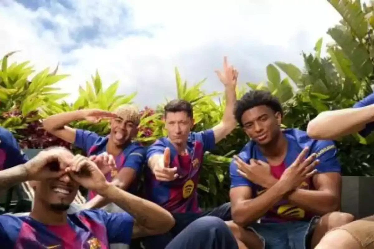 Jugadores del Barcelona posan sonrientes y haciendo gestos divertidos con las manos mientras usan el uniforme del equipo rodeados de vegetación Jugadores del Barcelona posan sonrientes y haciendo gestos divertidos con las manos mientras usan el uniforme del equipo rodeados de vegetación