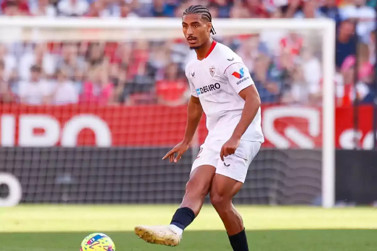 Futbolista con uniforme blanco del Sevilla FC controlando el balón en un partido
