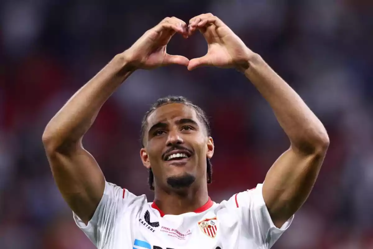 Futbolista del Sevilla sonríe y forma un corazón con las manos durante un partido