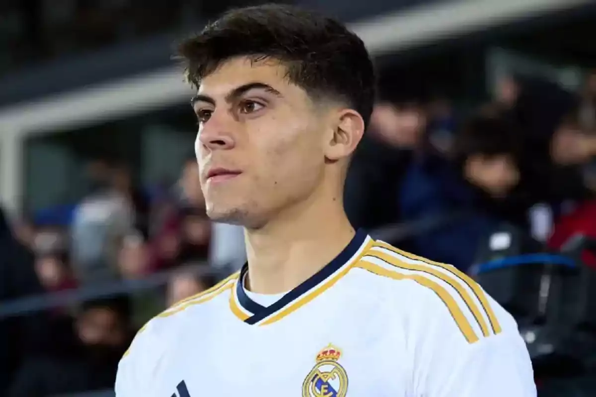 Young player wearing a white Real Madrid jersey in a stadium with a crowd in the background Young player wearing a white Real Madrid jersey in a stadium with a crowd in the background