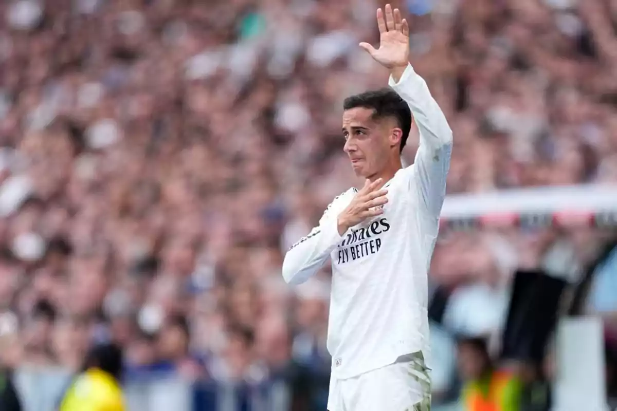 Futbolista con uniforme blanco saluda al público con una mano en el pecho y la otra levantada en un estadio lleno Futbolista con uniforme blanco saluda al público con una mano en el pecho y la otra levantada en un estadio lleno