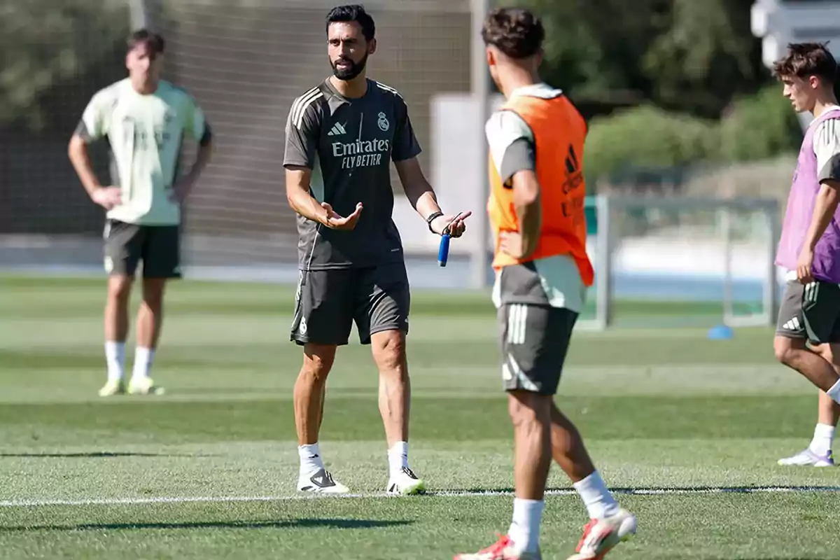 Entrenador de fútbol dando indicaciones a jugadores durante una práctica en campo de entrenamiento