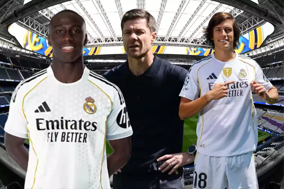 Tres personas con uniforme del Real Madrid posan en el interior de un estadio de fútbol moderno