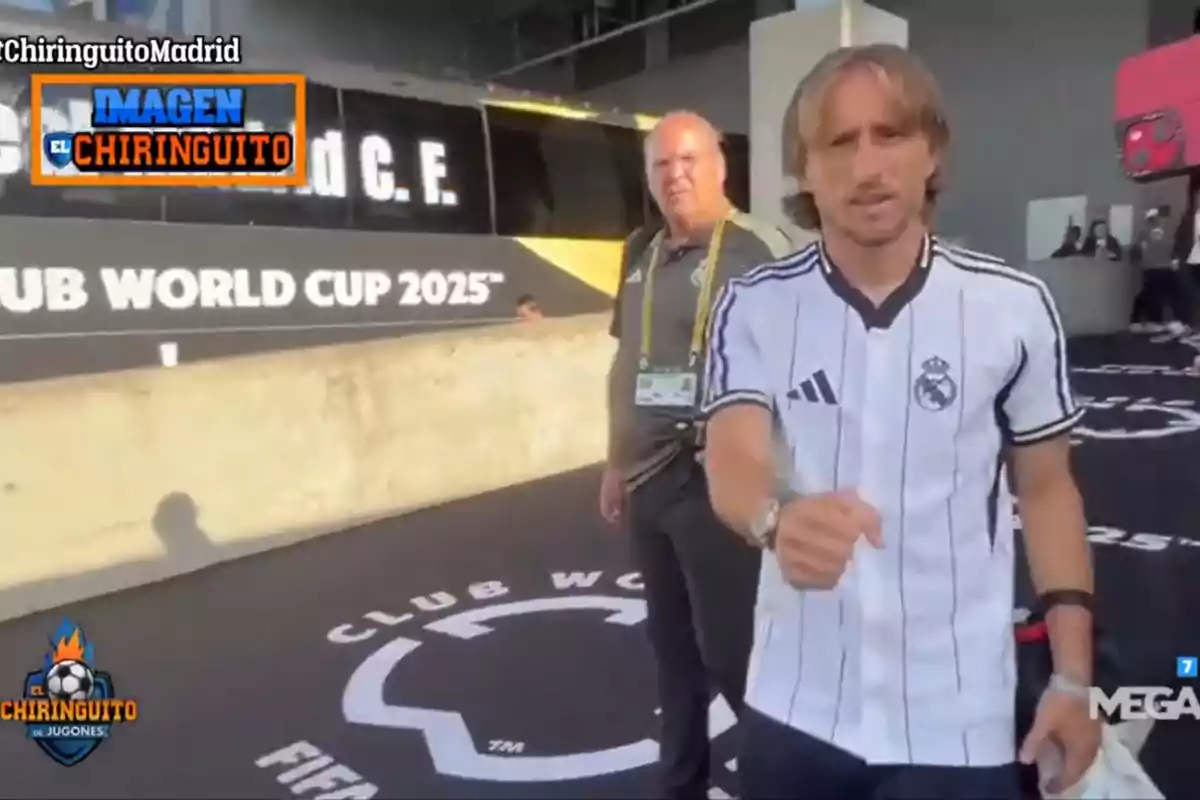 Real Madrid player in a black and white uniform walking next to another person in front of a bus with the text Club World Cup 2025 and El Chiringuito logos
