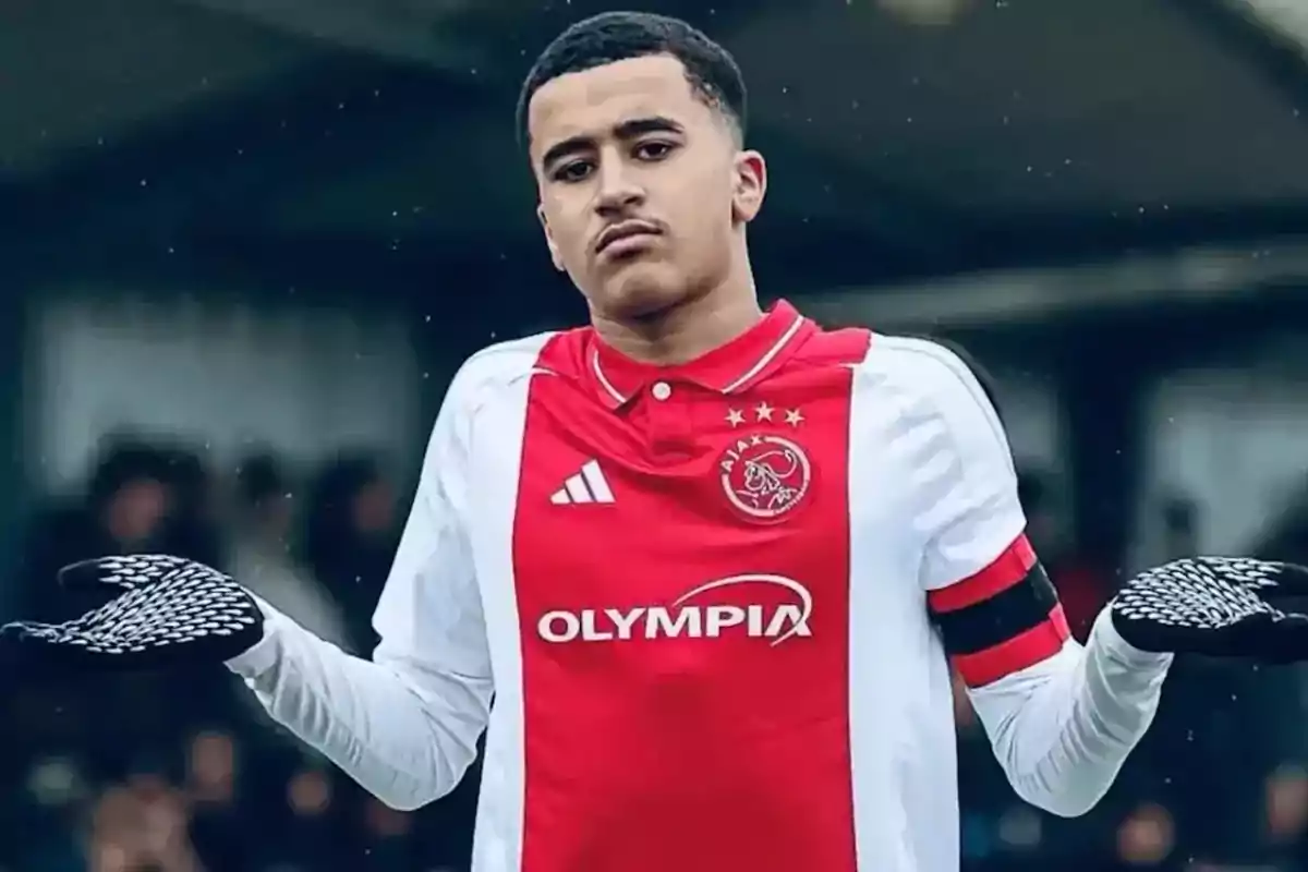 Joven futbolista con uniforme del Ajax haciendo un gesto de encogerse de hombros durante un partido