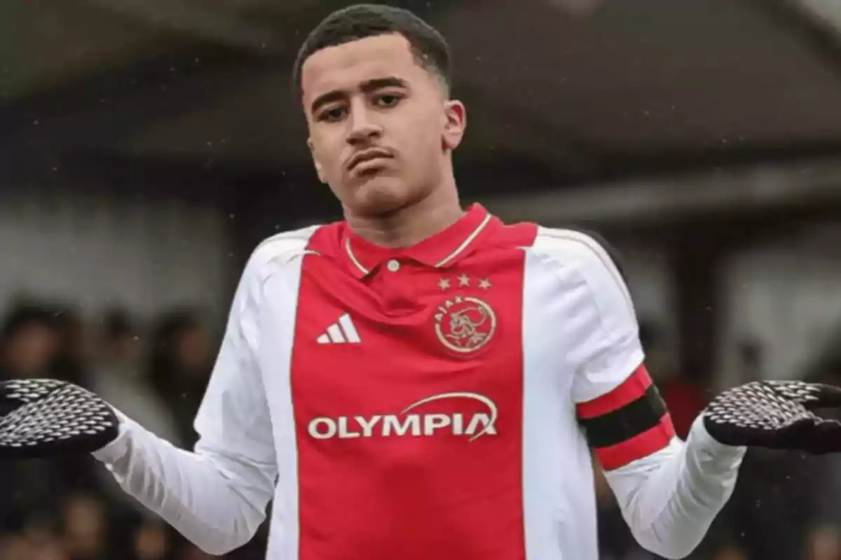Jugador de fútbol con uniforme del Ajax haciendo un gesto de encogimiento de hombros en el campo Jugador de fútbol con uniforme del Ajax haciendo un gesto de encogimiento de hombros en el campo