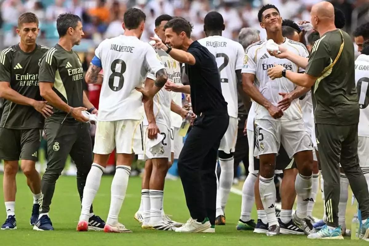 Real Madrid players and coaching staff talk and hydrate during a break in a soccer match. Real Madrid players and coaching staff talk and hydrate during a break in a soccer match.