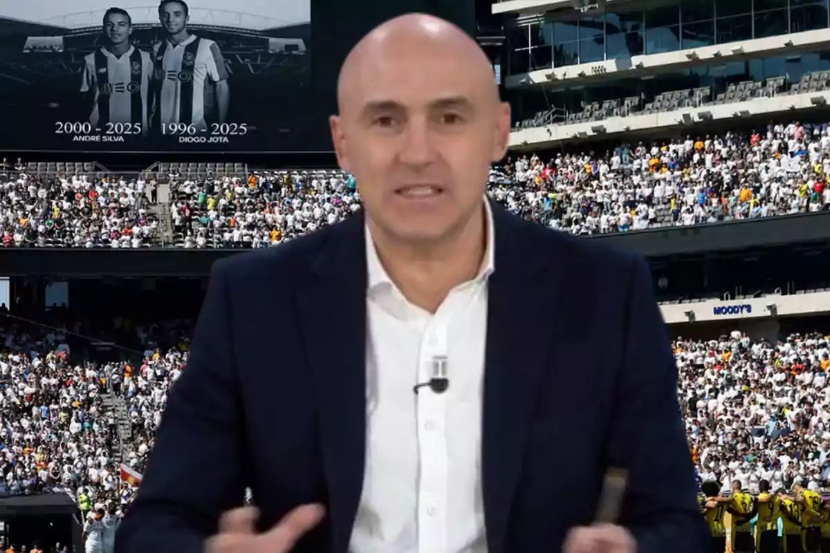 Un hombre calvo con saco oscuro y camisa blanca está hablando frente a un estadio lleno de gente, al fondo se ve una pantalla gigante con las imágenes de dos futbolistas y sus nombres.