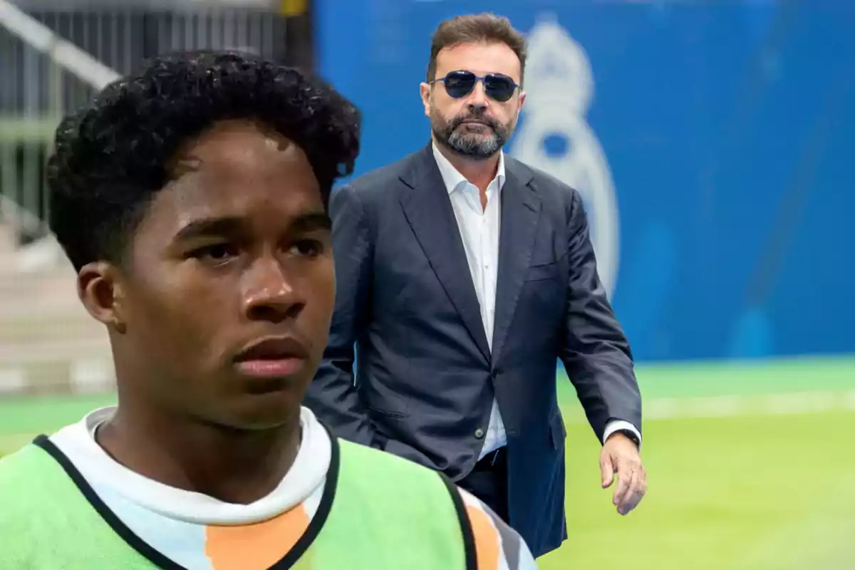Un joven futbolista con chaleco de entrenamiento en primer plano y un hombre con barba y gafas de sol vistiendo traje en el fondo sobre un campo de fútbol