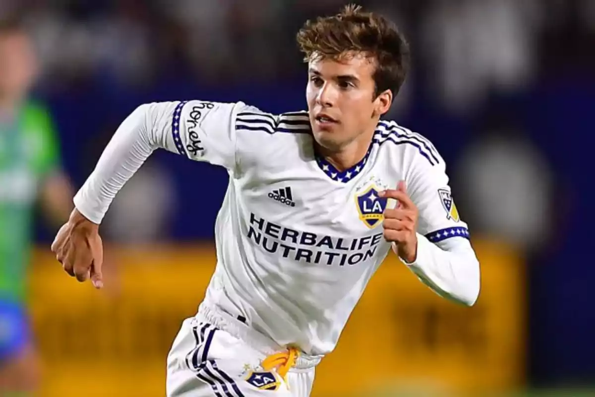 Soccer player in a white LA Galaxy uniform running on the field during a match Soccer player in a white LA Galaxy uniform running on the field during a match
