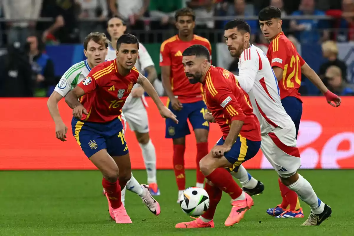 Spanish players and an opposing team compete for the ball during a match in a stadium full of spectators. Spanish players and an opposing team compete for the ball during a match in a stadium full of spectators.
