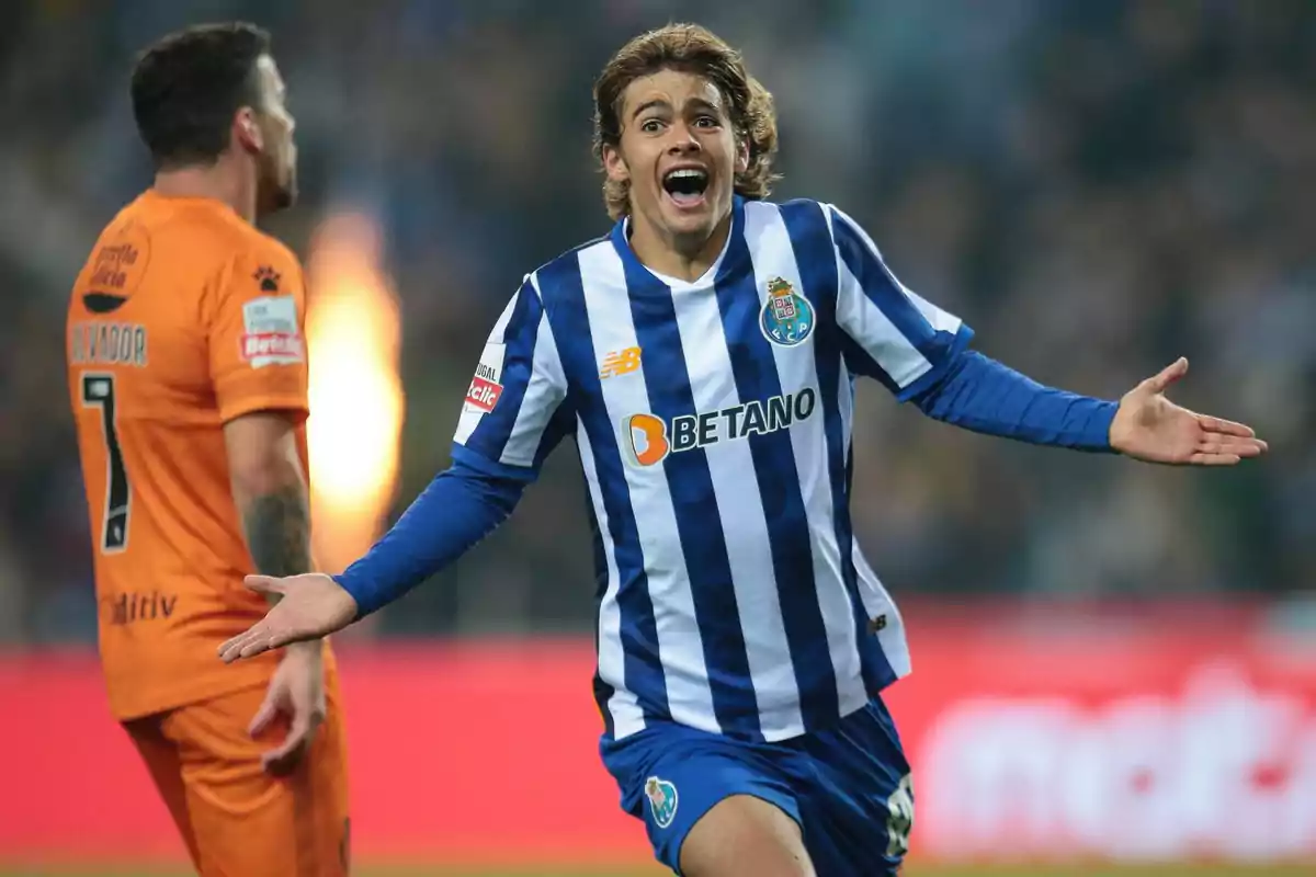 Porto player celebrating with arms outstretched while an opposing player in an orange uniform appears in the background Porto player celebrating with arms outstretched while an opposing player in an orange uniform appears in the background