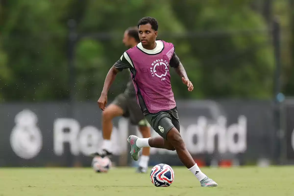 Futbolista entrenando en un campo de fútbol con un peto morado y un balón a sus pies Futbolista entrenando en un campo de fútbol con un peto morado y un balón a sus pies
