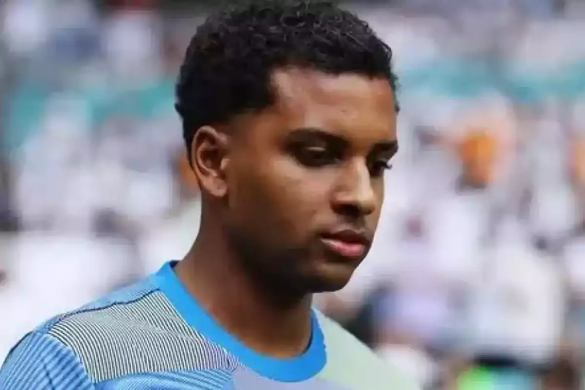Joven con camiseta deportiva azul mirando hacia abajo en un entorno de estadio desenfocado Joven con camiseta deportiva azul mirando hacia abajo en un entorno de estadio desenfocado