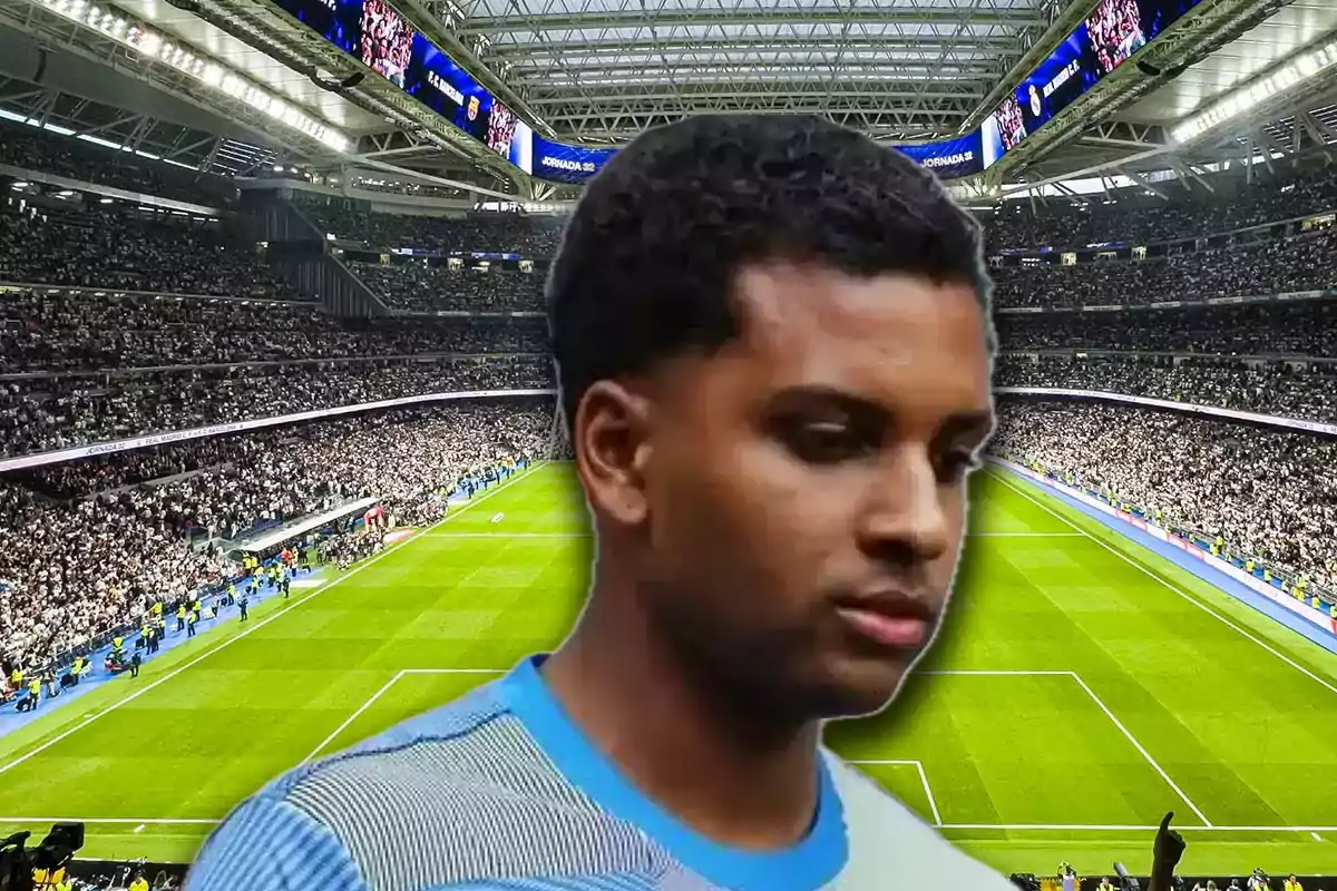 Un futbolista con expresión seria aparece en primer plano sobre el fondo de un estadio lleno de aficionados
