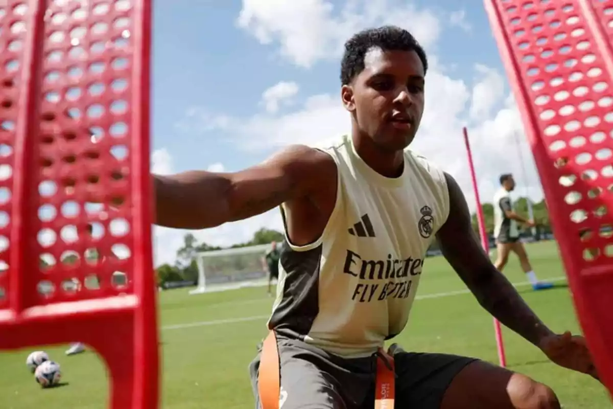 Futbolista del Real Madrid entrenando en un campo de fútbol con equipo de entrenamiento rojo y césped verde Futbolista del Real Madrid entrenando en un campo de fútbol con equipo de entrenamiento rojo y césped verde