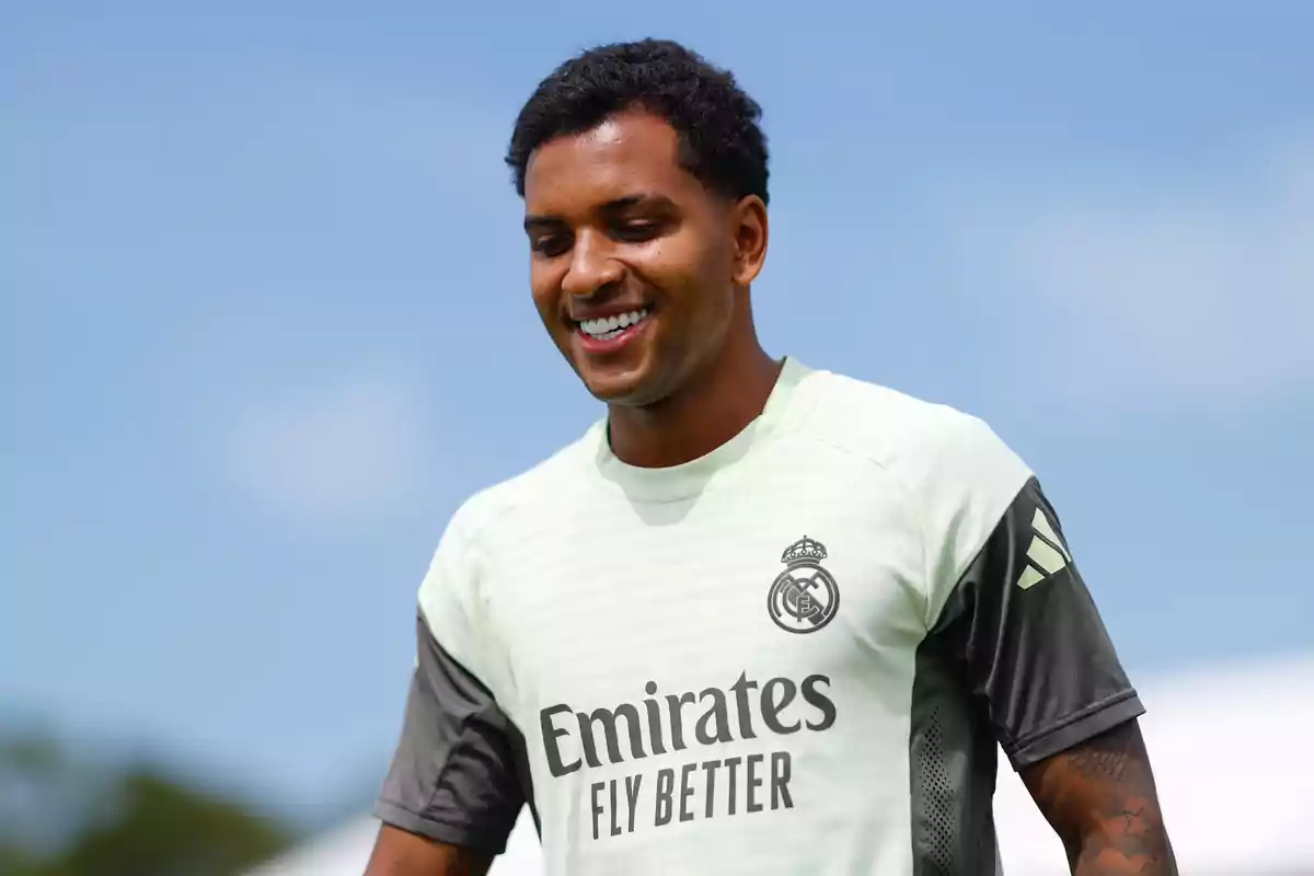 Futbolista sonriente con camiseta de entrenamiento del Real Madrid sobre un fondo de cielo azul Futbolista sonriente con camiseta de entrenamiento del Real Madrid sobre un fondo de cielo azul