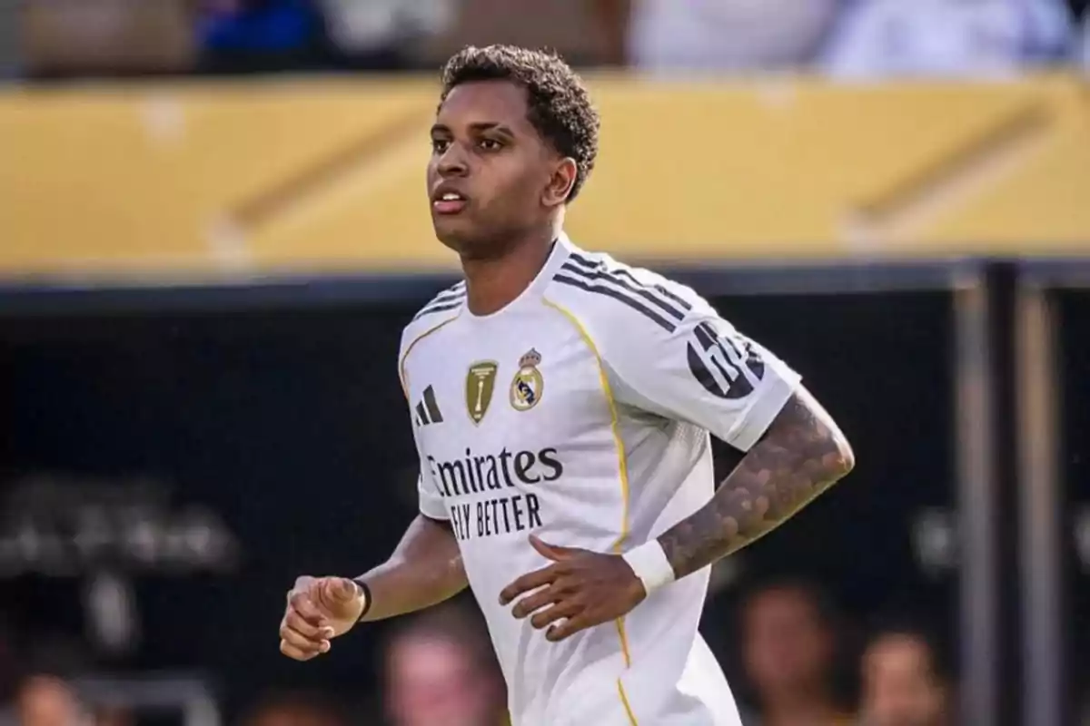Futbolista con uniforme blanco del Real Madrid corriendo en el campo durante un partido