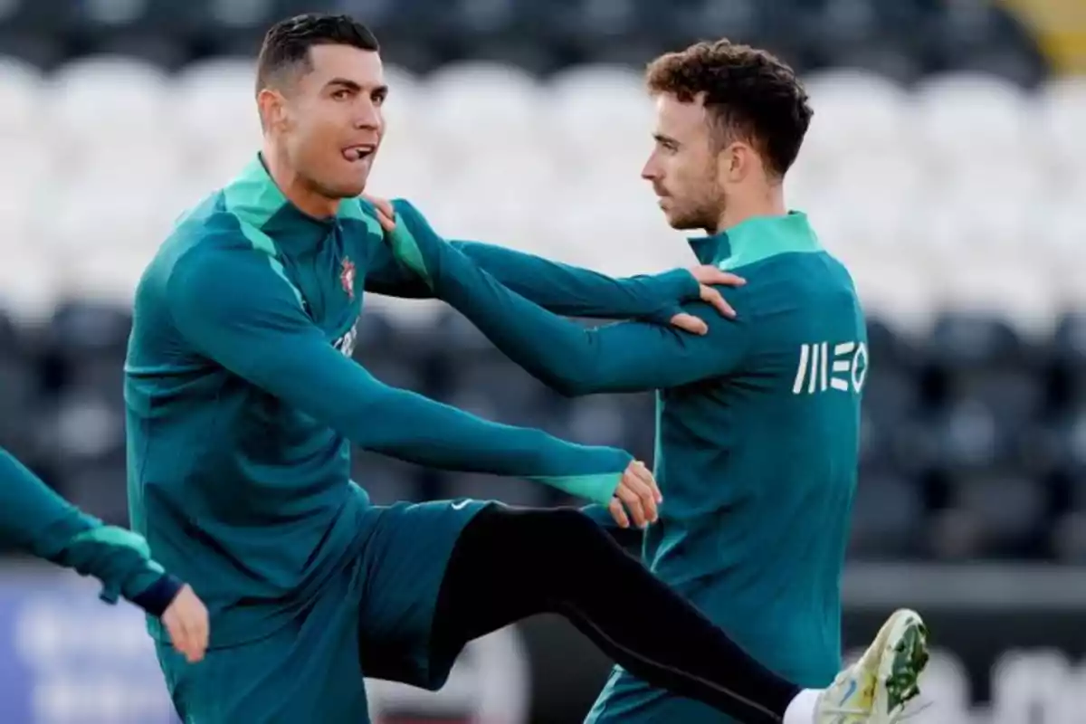 Dos futbolistas con uniforme verde realizan ejercicios de calentamiento en un campo de entrenamiento Dos futbolistas con uniforme verde realizan ejercicios de calentamiento en un campo de entrenamiento