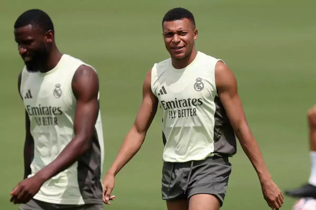 Two players in Real Madrid training uniforms walk on the grass during a practice. Two players in Real Madrid training uniforms walk on the grass during a practice.