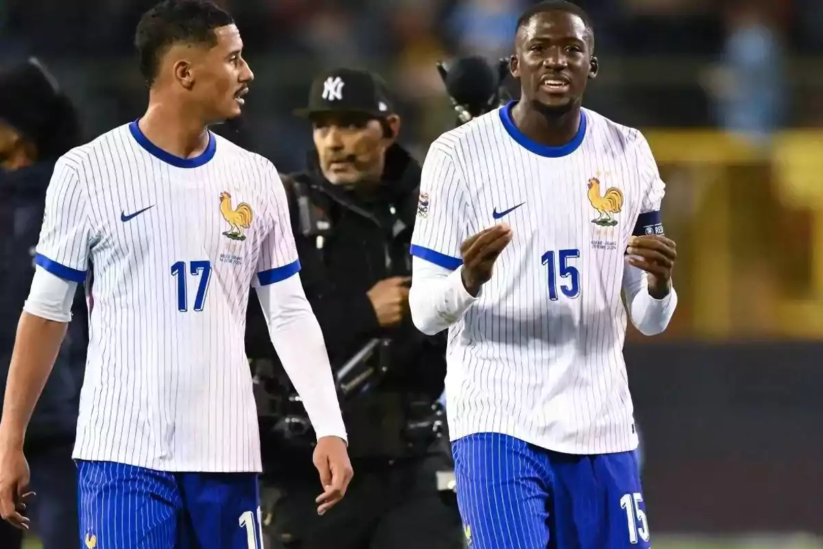 Dos futbolistas con uniforme blanco y azul de la selección de Francia conversan en el campo durante un partido Dos futbolistas con uniforme blanco y azul de la selección de Francia conversan en el campo durante un partido