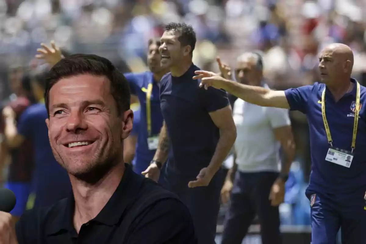 Un hombre sonriente en primer plano y varias personas discutiendo en el fondo durante un partido de fútbol