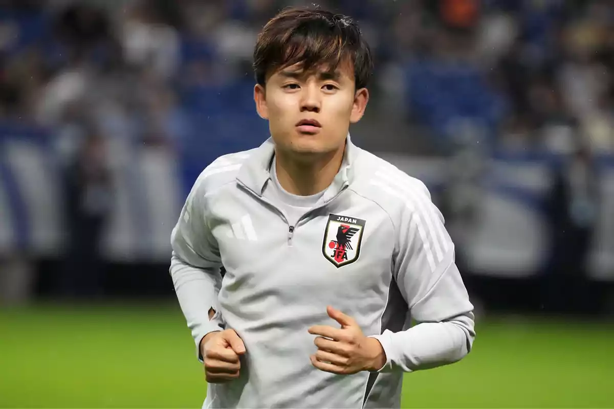 Japanese player in a gray training jacket during warm-up at a stadium Japanese player in a gray training jacket during warm-up at a stadium