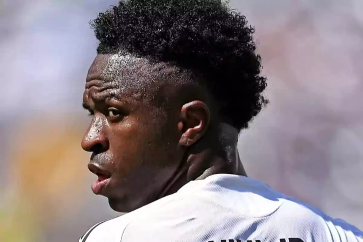 Jugador de fútbol con camiseta blanca mirando hacia atrás durante un partido