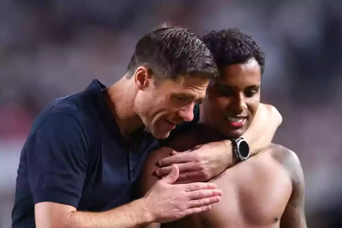 Entrenador abrazando y hablando con un jugador de fútbol sin camiseta en el campo Entrenador abrazando y hablando con un jugador de fútbol sin camiseta en el campo
