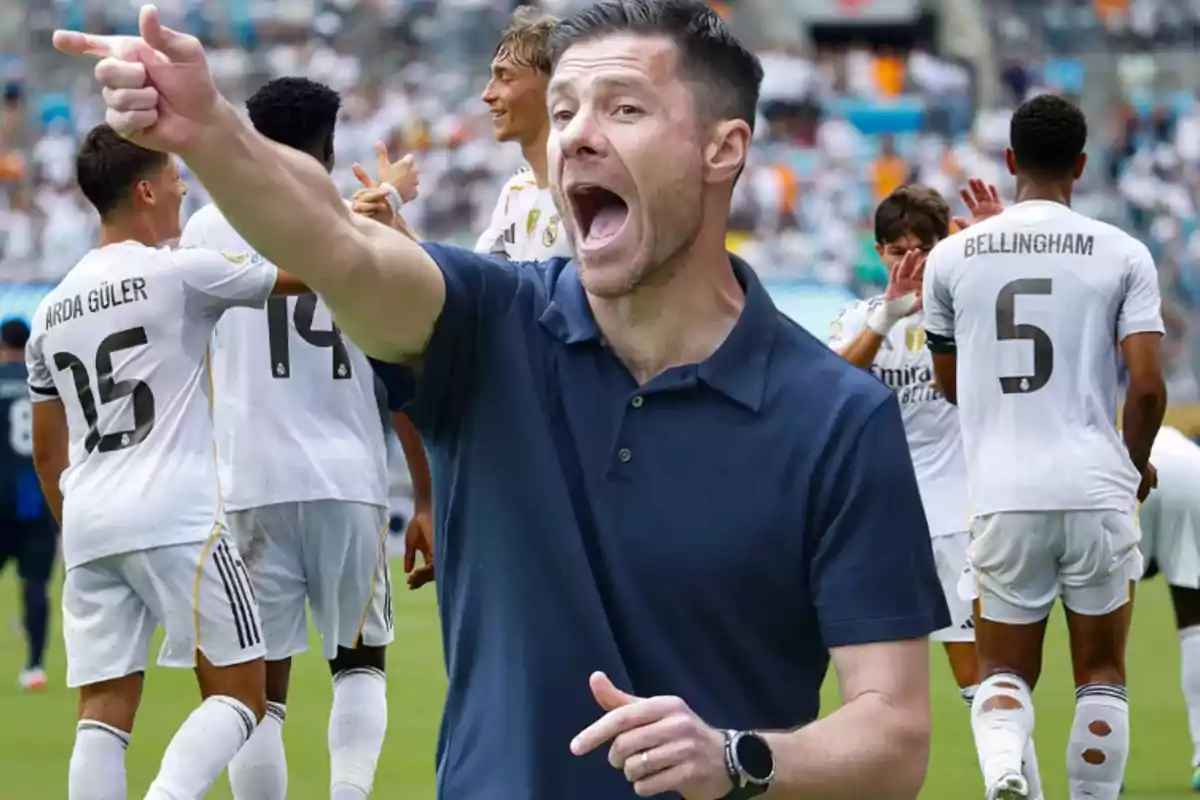 Soccer coach giving instructions in the foreground while team players celebrate on the field in the background