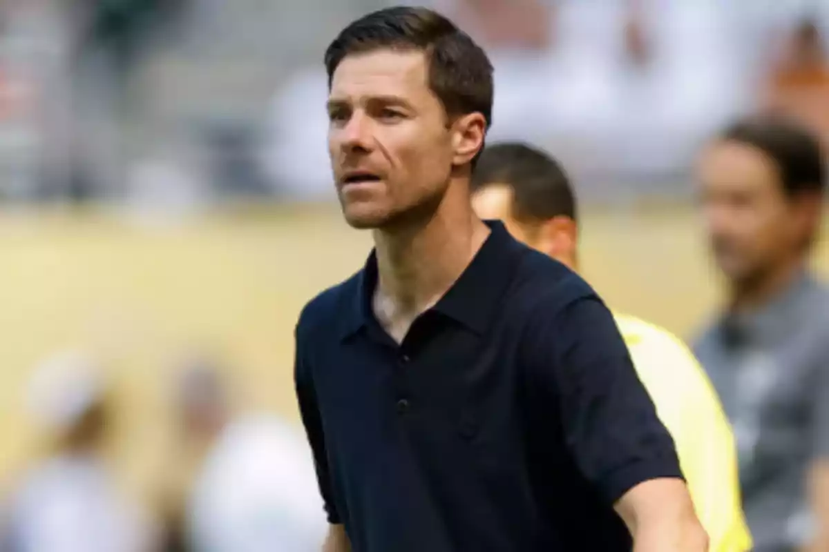 Hombre de cabello corto y barba ligera vistiendo una camisa polo oscura en un entorno deportivo Hombre de cabello corto y barba ligera vistiendo una camisa polo oscura en un entorno deportivo