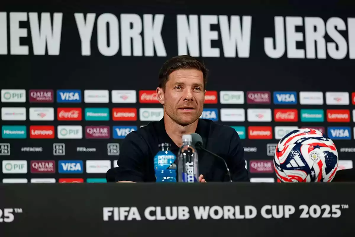 Man sitting at a press conference with a microphone in front of him, a bottle of water and a soccer ball on the table, with the text FIFA Club World Cup 2025 and a background with sponsor logos and the words New York New Jersey. Man sitting at a press conference with a microphone in front of him, a bottle of water and a soccer ball on the table, with the text FIFA Club World Cup 2025 and a background with sponsor logos and the words New York New Jersey.