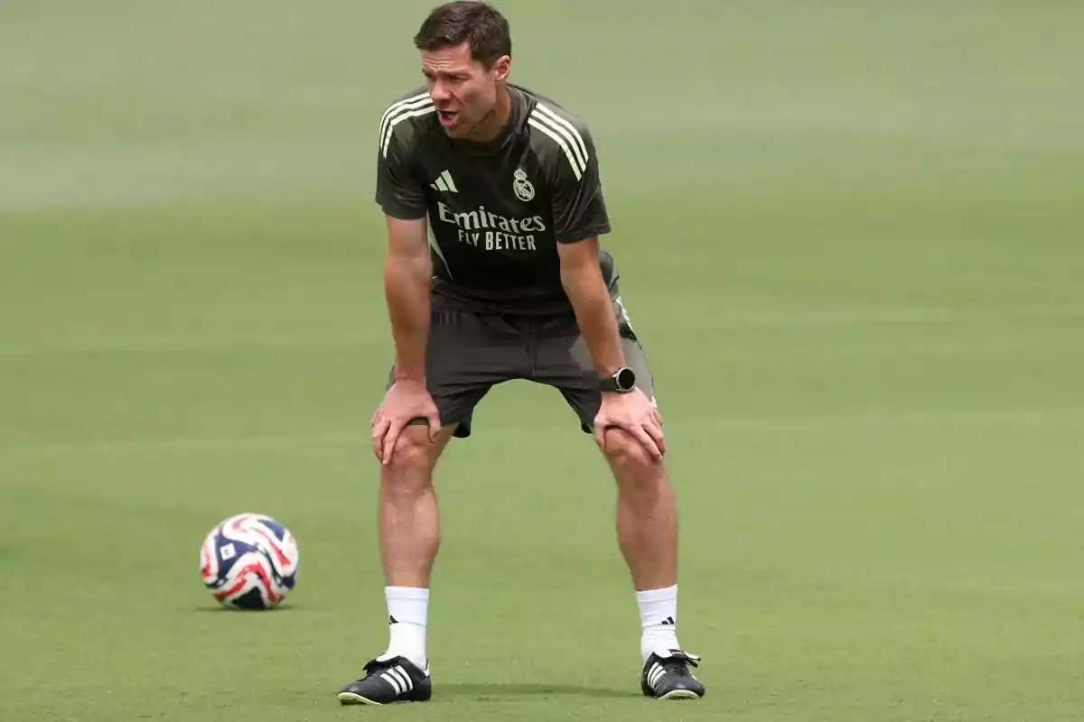 Soccer coach in a Real Madrid uniform watching the field during a training session with a ball near him