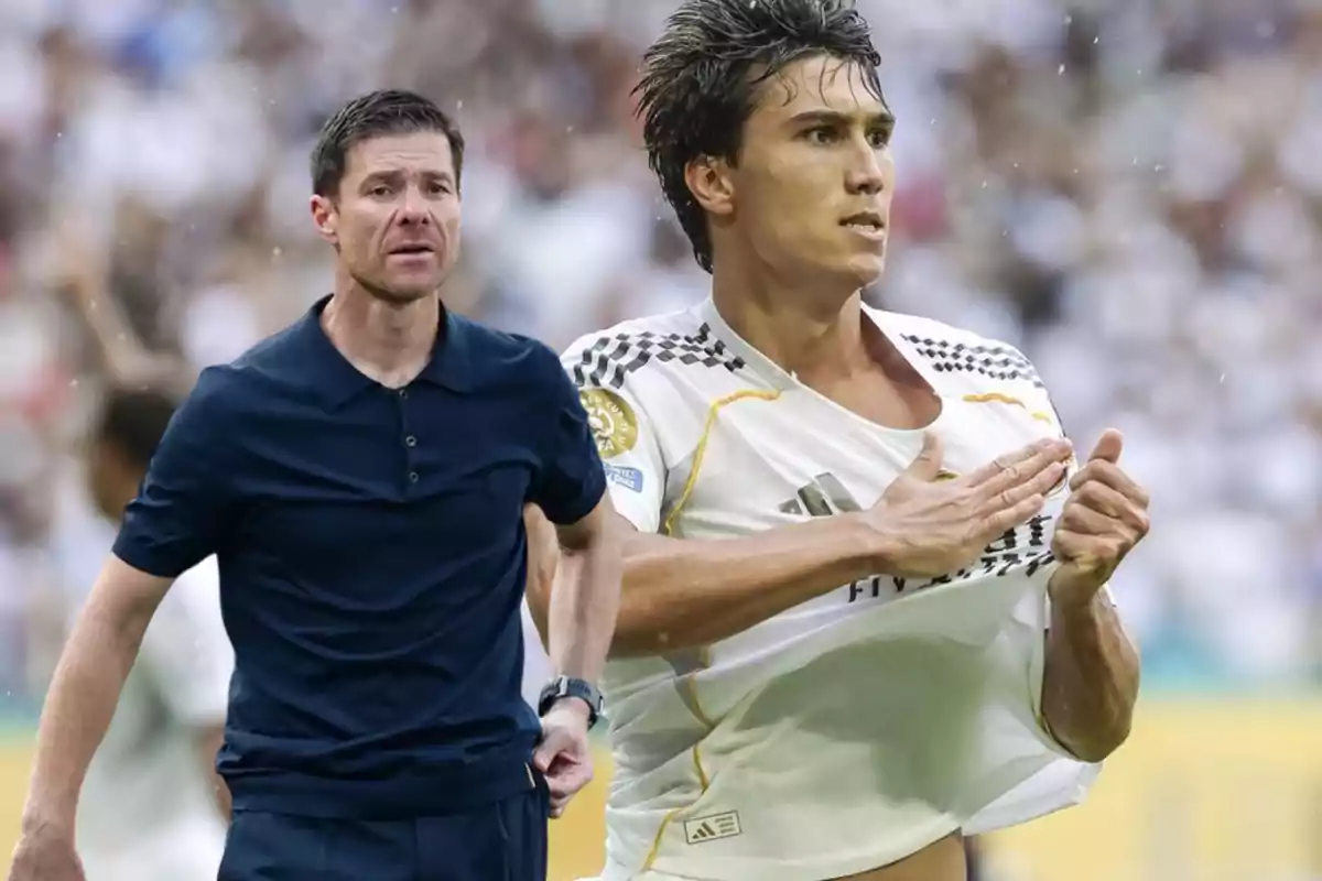 Entrenador de fútbol con camisa azul oscuro y jugador celebrando con camiseta blanca en un estadio lleno de público