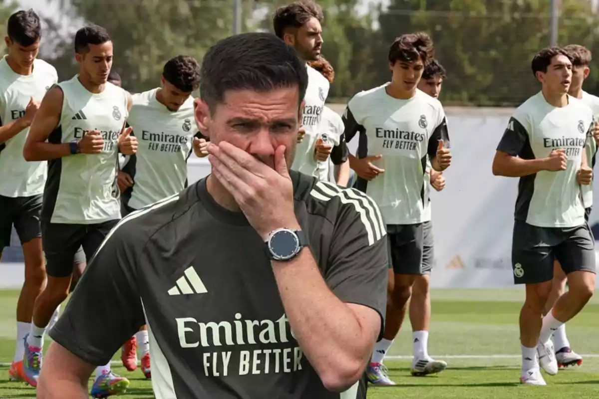 Entrenador de fútbol con gesto pensativo al frente mientras un grupo de jugadores del Real Madrid entrena corriendo en el campo