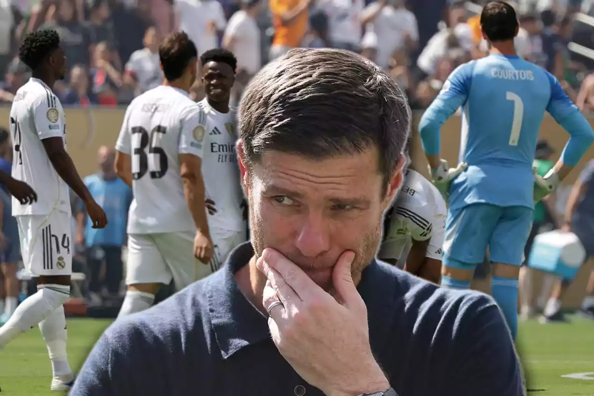 Un hombre pensativo en primer plano con jugadores de fútbol del Real Madrid al fondo en un estadio